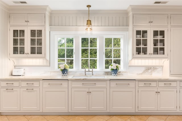 kitchen featuring white cabinets, decorative light fixtures, and a wealth of natural light