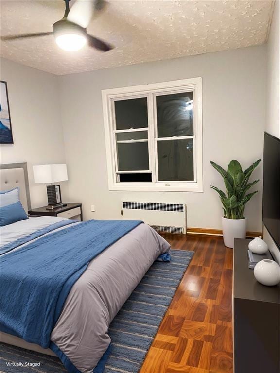 bedroom with ceiling fan, a textured ceiling, radiator, and dark wood-type flooring