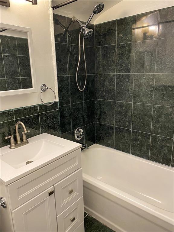 bathroom with tiled shower / bath combo, tile walls, vanity, and tasteful backsplash