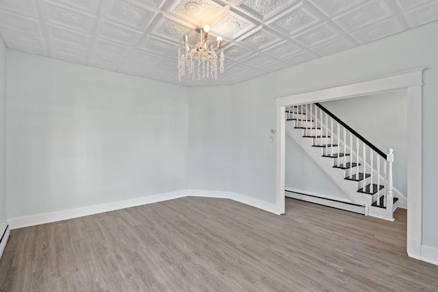 29 Thompson St, Port Jervis, NY 12771 - empty room with wood finished floors, stairway, a notable chandelier, and a baseboard radiator