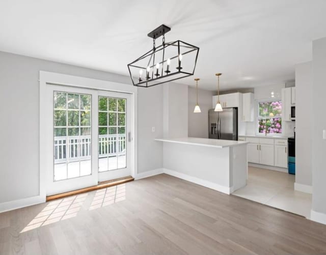 kitchen with decorative light fixtures, white cabinets, light hardwood / wood-style floors, kitchen peninsula, and stainless steel fridge with ice dispenser