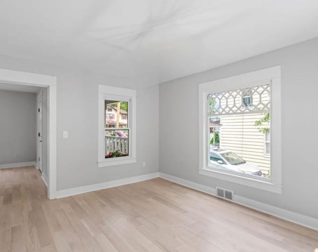 empty room with a healthy amount of sunlight and light hardwood / wood-style floors