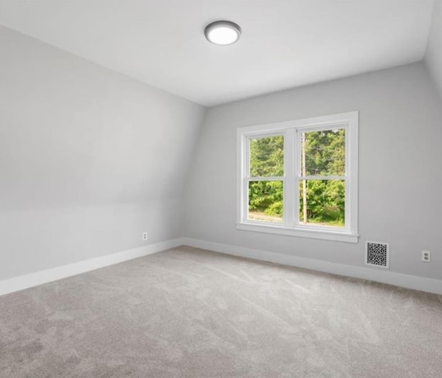 unfurnished room featuring lofted ceiling and carpet flooring