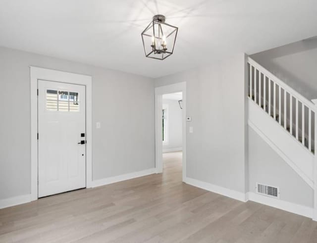 entryway with light hardwood / wood-style floors and a chandelier