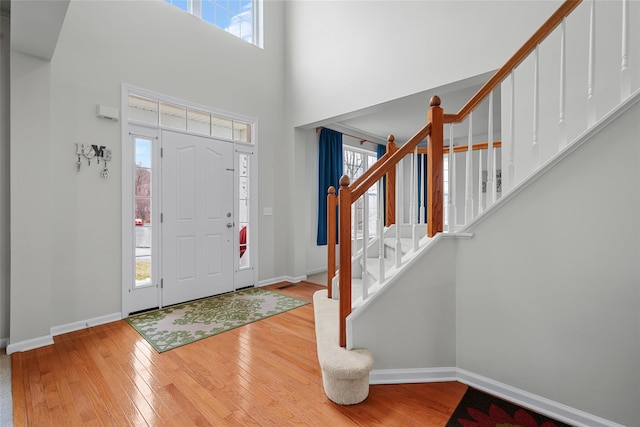 foyer featuring a healthy amount of sunlight, light wood-type flooring, and a high ceiling