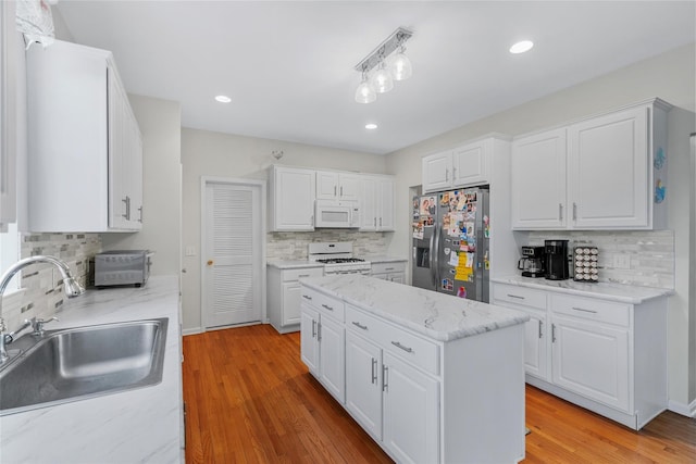 kitchen with sink, decorative backsplash, white appliances, and white cabinetry