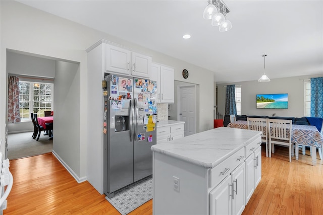 kitchen featuring white cabinetry, light hardwood / wood-style floors, hanging light fixtures, stainless steel refrigerator with ice dispenser, and a kitchen island