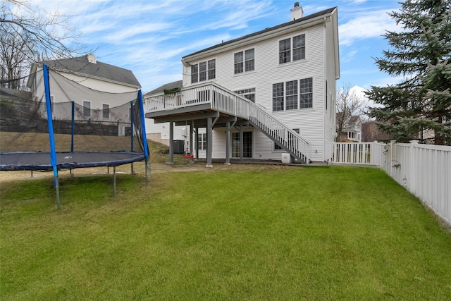 back of property with a yard, central AC unit, a trampoline, and a wooden deck