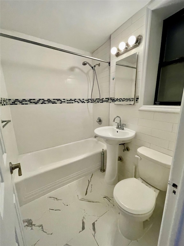 bathroom with tiled shower / bath combo, toilet, and tile walls