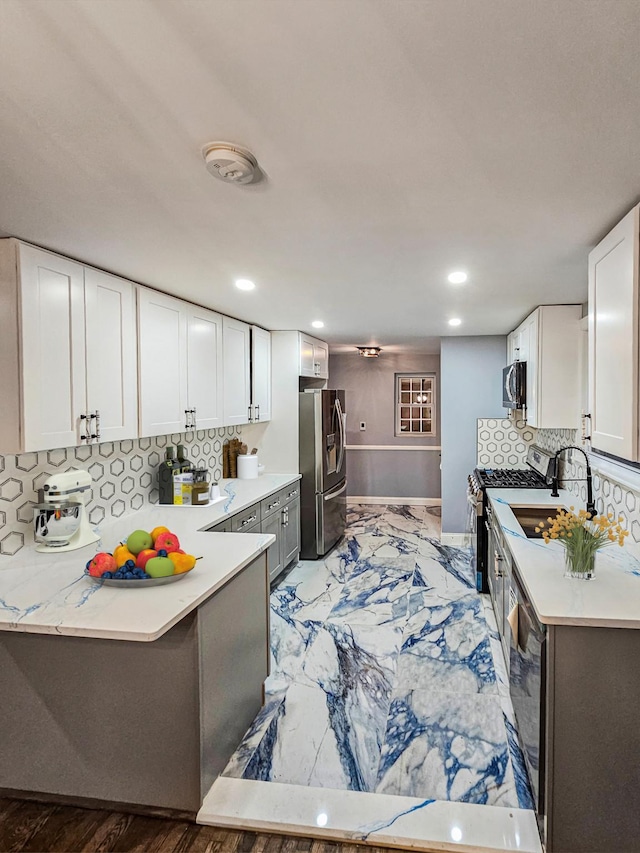 kitchen with backsplash, stainless steel appliances, white cabinetry, and sink