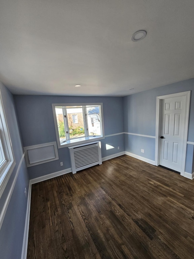 spare room featuring radiator heating unit and dark hardwood / wood-style flooring