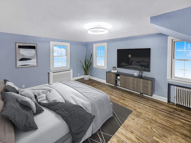 bedroom featuring dark hardwood / wood-style floors, vaulted ceiling, and radiator