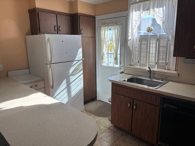 kitchen with dark brown cabinets, sink, light tile patterned floors, white refrigerator, and black dishwasher