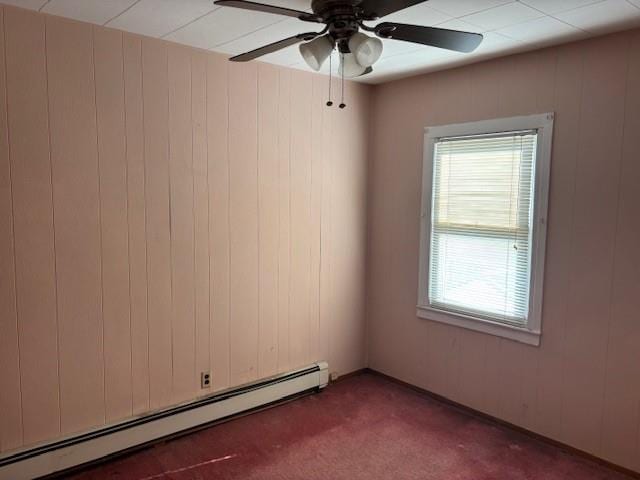 empty room featuring carpet, a baseboard radiator, ceiling fan, and wooden walls