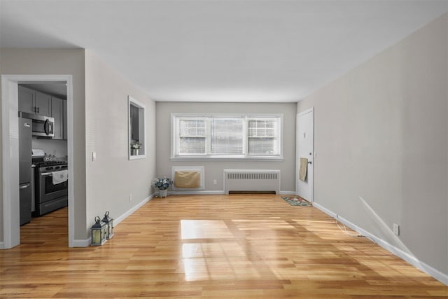 empty room with radiator heating unit and light hardwood / wood-style flooring