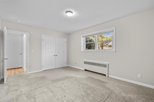 unfurnished bedroom with light colored carpet, radiator heating unit, and a closet