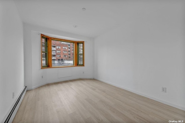 spare room with light wood-type flooring and a baseboard radiator