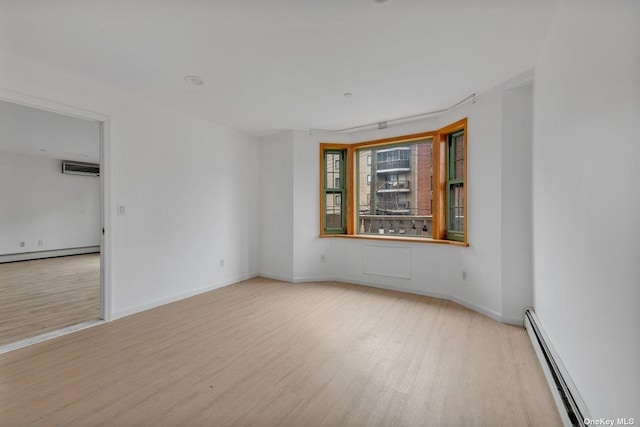 unfurnished room featuring light wood-type flooring, a wall mounted AC, and a baseboard radiator