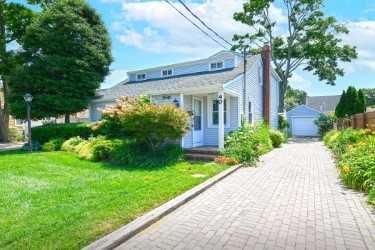 bungalow-style home with a garage, an outbuilding, and a front lawn