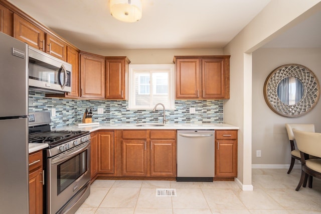 kitchen with tasteful backsplash, light tile patterned floors, sink, and stainless steel appliances