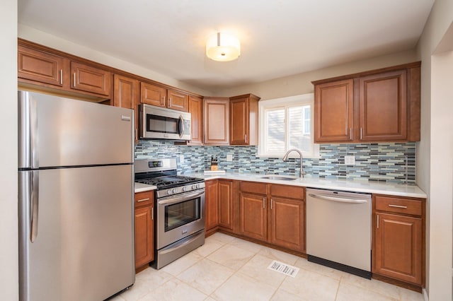 kitchen featuring light tile patterned floors, sink, appliances with stainless steel finishes, and tasteful backsplash