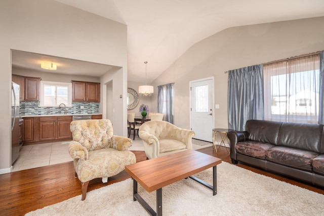 living room featuring vaulted ceiling, light wood-type flooring, and sink