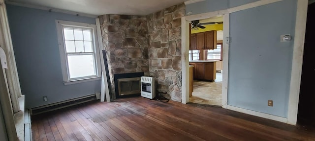 unfurnished living room featuring dark hardwood / wood-style flooring, heating unit, plenty of natural light, and ceiling fan