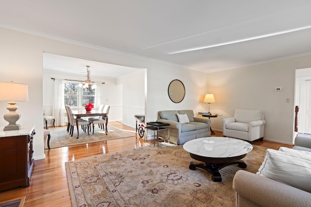 living room featuring ornamental molding, light hardwood / wood-style floors, and a notable chandelier