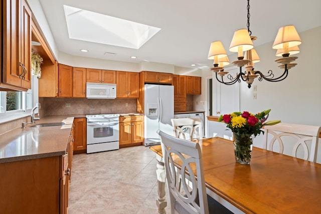 kitchen featuring sink, white appliances, tasteful backsplash, a skylight, and pendant lighting