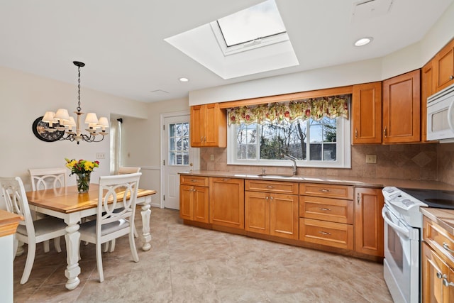 kitchen featuring white appliances, a skylight, pendant lighting, sink, and backsplash