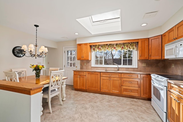 kitchen featuring white appliances, a chandelier, a skylight, pendant lighting, and decorative backsplash