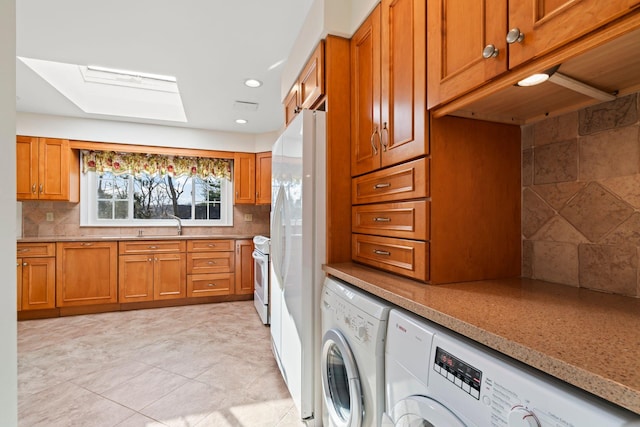 kitchen featuring a skylight, white appliances, tasteful backsplash, and separate washer and dryer