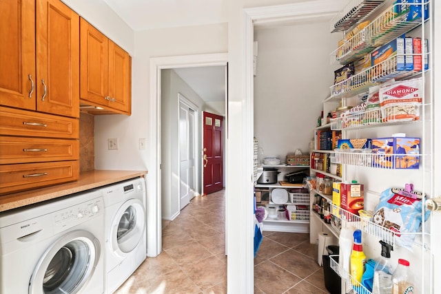 clothes washing area with separate washer and dryer, cabinets, and light tile patterned floors