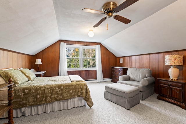 carpeted bedroom featuring ceiling fan, baseboard heating, vaulted ceiling, and wood walls