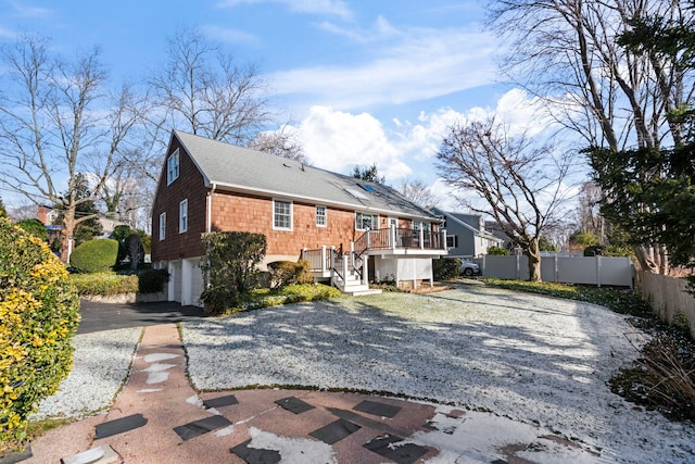 rear view of property featuring a garage and a wooden deck