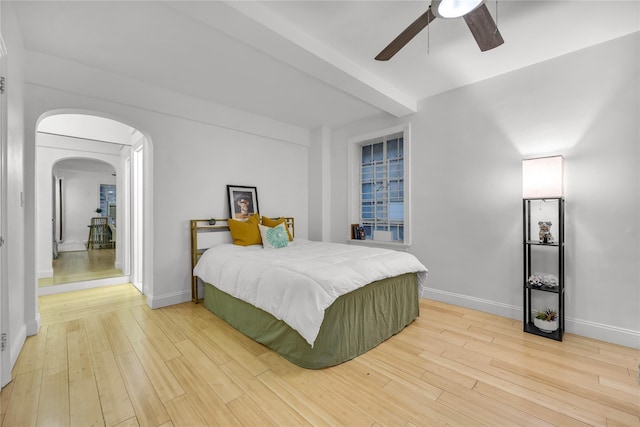 bedroom with arched walkways, baseboards, and wood finished floors