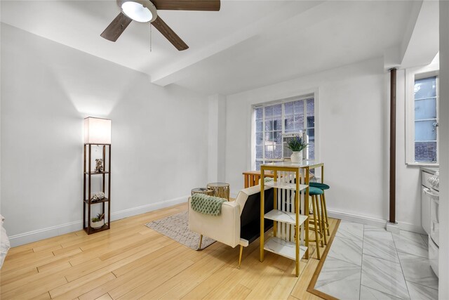 living area with a ceiling fan, baseboards, and wood finished floors