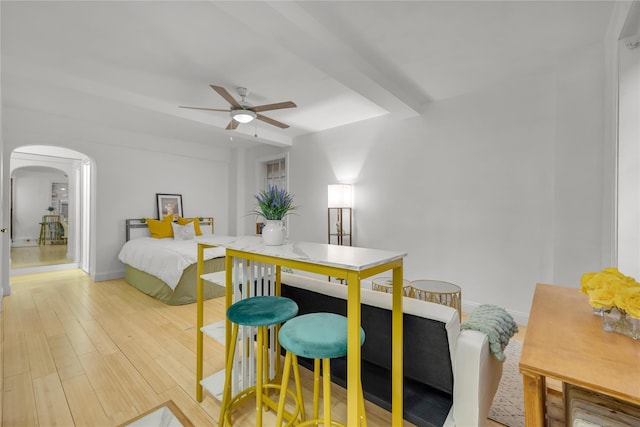 bedroom with baseboards, light wood-type flooring, arched walkways, and a ceiling fan