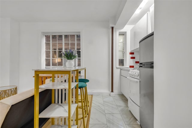 kitchen featuring white cabinets, baseboards, marble finish floor, modern cabinets, and white range with gas cooktop