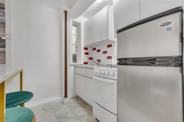 kitchen with white cabinets, marble finish floor, tasteful backsplash, gas range gas stove, and freestanding refrigerator
