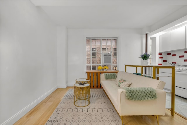 sitting room featuring baseboards, cooling unit, and light wood-style floors