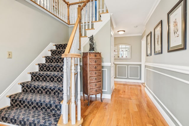 staircase featuring wood-type flooring and ornamental molding