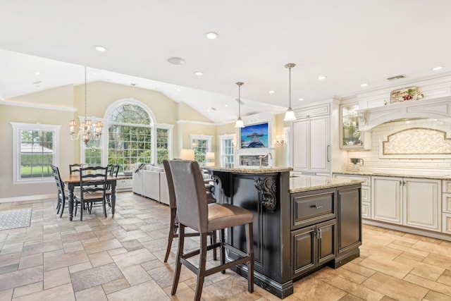 kitchen featuring hanging light fixtures, a kitchen breakfast bar, light stone counters, vaulted ceiling, and a kitchen island