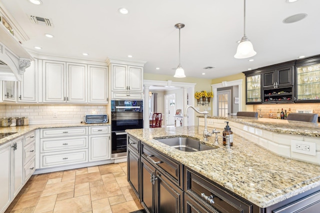 kitchen with pendant lighting, dark brown cabinets, sink, and black double oven