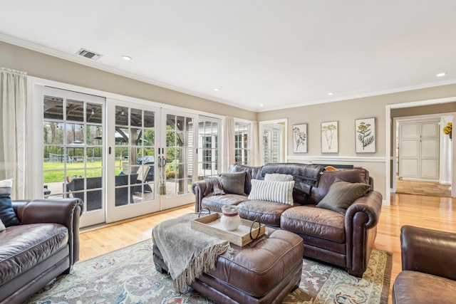 living room with french doors, light wood-type flooring, and ornamental molding