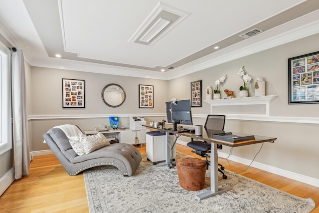 office featuring light hardwood / wood-style floors, ornamental molding, and a tray ceiling