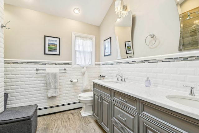 bathroom with baseboard heating, vanity, tile walls, and toilet