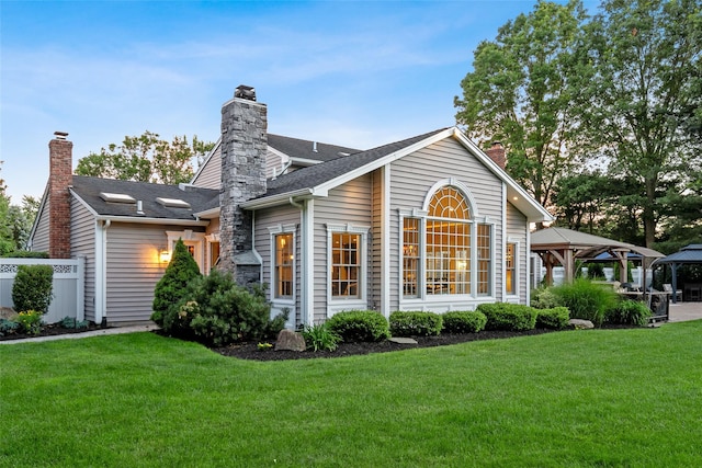 rear view of property featuring a gazebo and a yard