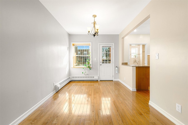 unfurnished dining area with a baseboard heating unit, light wood-type flooring, and an inviting chandelier