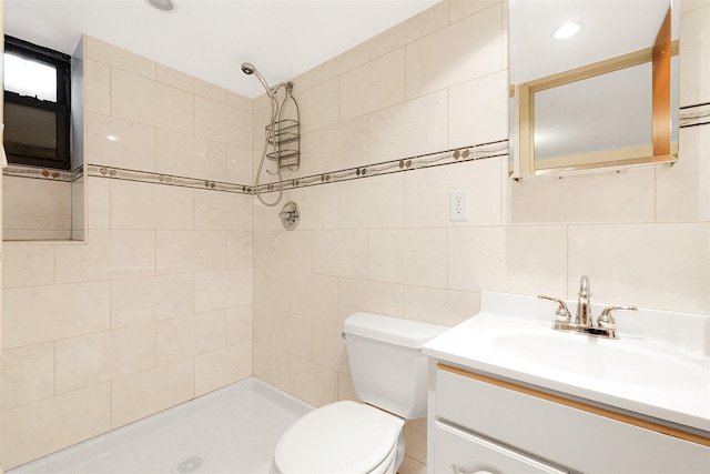 bathroom with toilet, tiled shower, tasteful backsplash, tile walls, and vanity